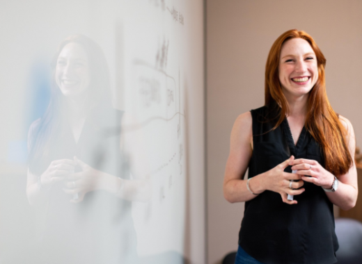 Smiling Woman Wearing Black Dress Standing in Front of a Room